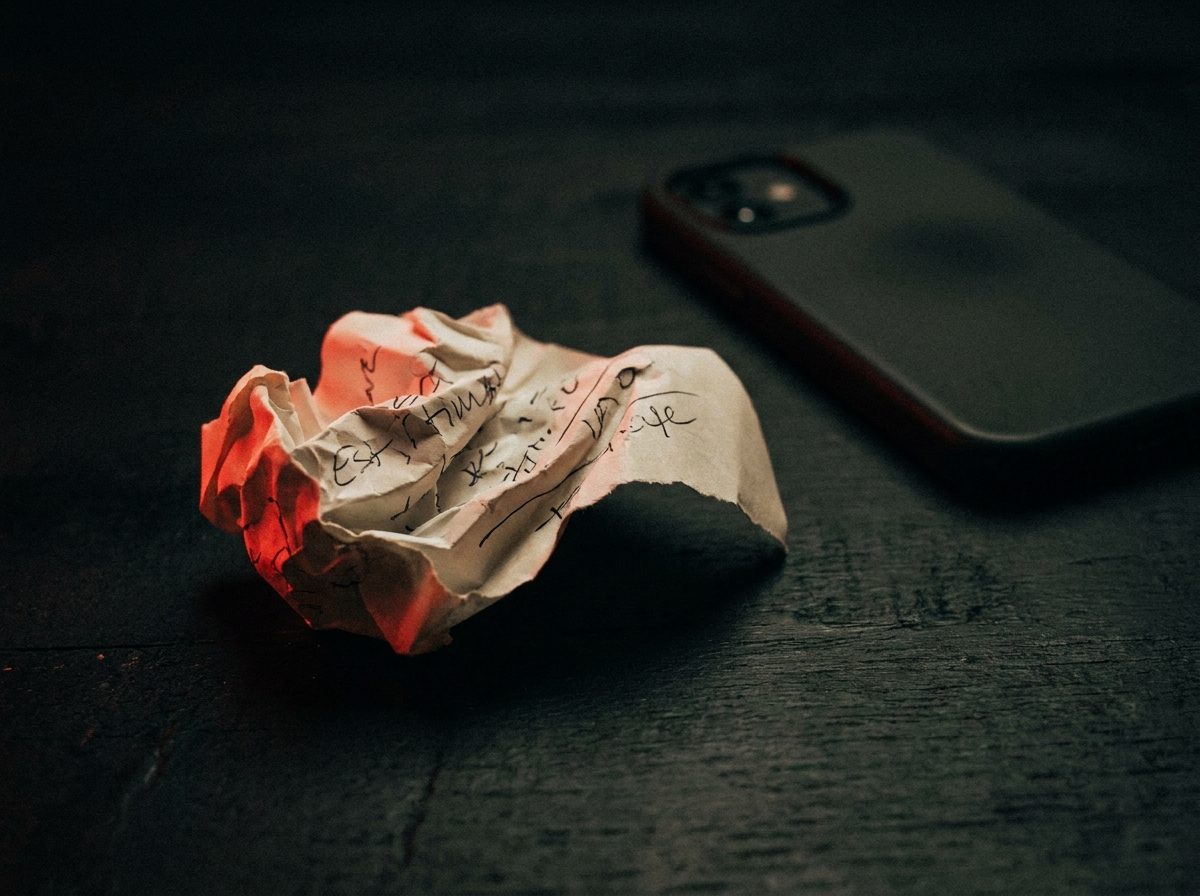 A crumpled paper estimate on a dark desk next to a phone left face-down, representing a quote nobody followed up on